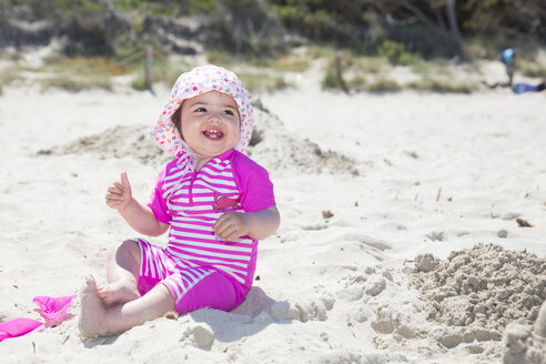 Spanien, Mallorca, lächelndes kleines Mädchen am Strand sitzend - ROMF000062