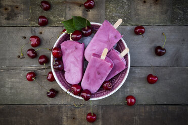 Bowl of cherry yoghurt ice lollies and cherries on wood - LVF003562