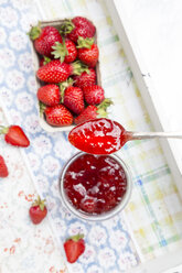 Löffel mit Erdbeermarmelade und Schachtel mit Erdbeeren im Hintergrund - LVF003559
