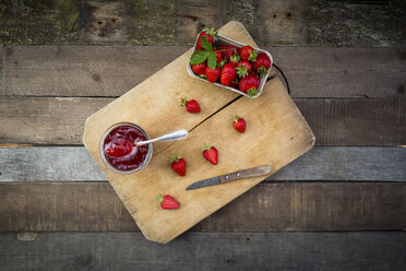 Glass of homemade strawberry jam and box of strawberries on wood - LVF003552