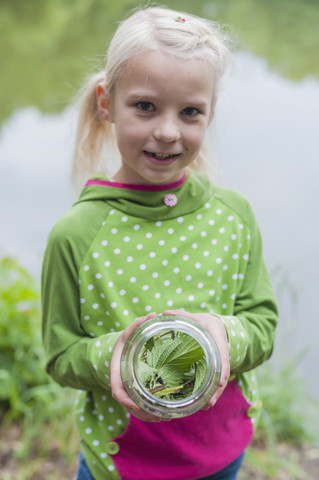 Deutschland, Mädchen hält Glas mit Raupe des Tagpfauenauges, lizenzfreies Stockfoto