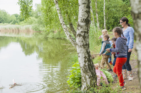 Germany, Children watching toy raft in water stock photo