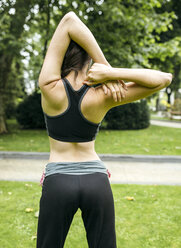 Spain, Oviedo, back view of young woman doing stretching exercises - MGOF000303