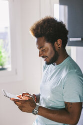 Lächelnder junger Mann, der sein Phablet zu Hause benutzt - EBSF000698