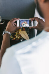 Junger Mann, der sein zubereitetes Essen mit dem Smartphone in der Küche fotografiert - EBSF000707