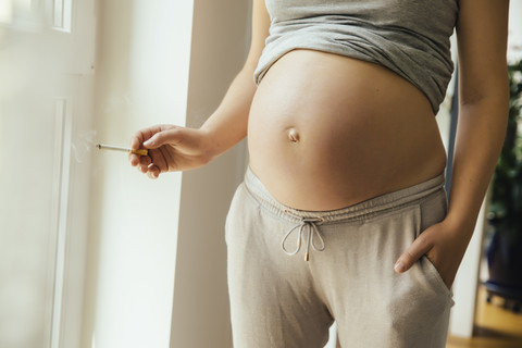 Pregnant woman holding a cigarette stock photo