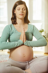 Porträt einer schwangeren Frau, die zu Hause meditiert - MFF001672