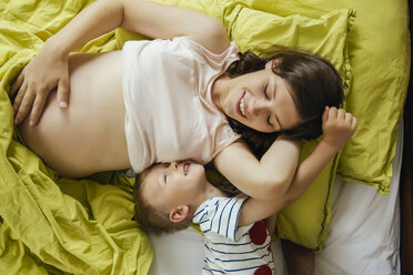 Schwangere Mutter und ihr Sohn kuscheln zu Hause im Bett - MFF001780
