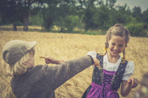 Deutschland, Sachsen, zwei Kinder spielen auf einem Getreidefeld - MJF001579