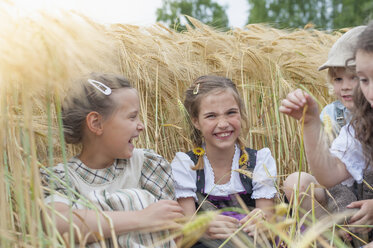 Deutschland, Sachsen, Kinder sitzen in einem Getreidefeld und haben Spaß - MJF001584