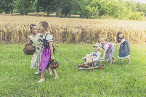 Deutschland, Sachsen, fünf Kinder mit Wagen auf einer Wiese - MJF001588