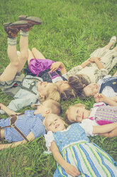 Deutschland, Sachsen, Gruppe von Kindern in traditioneller Kleidung auf einer Wiese im Kreis liegend - MJF001598