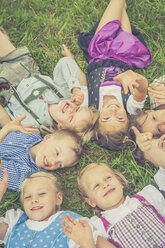 Deutschland, Sachsen, Gruppe von Kindern in traditioneller Kleidung auf einer Wiese im Kreis liegend - MJF001599