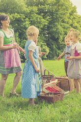 Deutschland, Sachsen, Kinder und ihre Erzieherin in traditioneller Kleidung auf einer Wiese - MJF001605