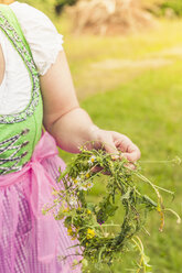 Deutschland, Sachsen, Frau im Dirndl hält Blumenkranz, Nahaufnahme - MJF001606