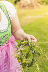 Germany, Saxony, woman wearing dirndl holding floral wreath, close-up - MJF001606