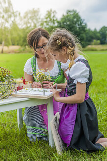 Germany, Saxony, girl wearing dirndl learning to draw plants - MJF001609