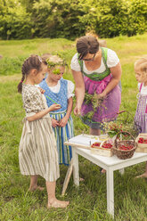 Germany, Saxony, three little girls and their educator in traditonal clothes on a meadow - MJF001613