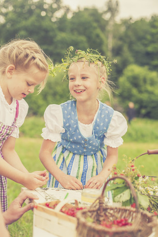 Deutschland, Sachsen, Porträt eines lächelnden kleinen Mädchens mit Blumenkranz, lizenzfreies Stockfoto