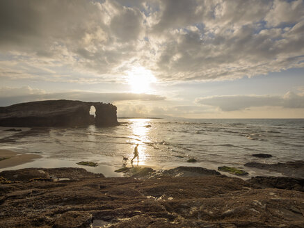 Spanien, Galicien, Ribadeo, Playa de Aguas Santas bei Sonnenuntergang, Mensch und Hund am Strand - LAF001410