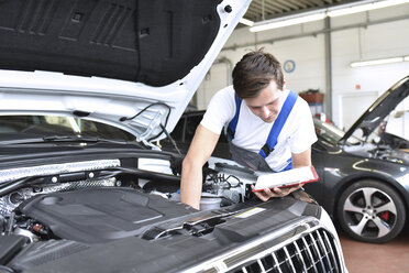 Mechaniker untersucht den Motor eines Autos in einer Werkstatt - LYF000443