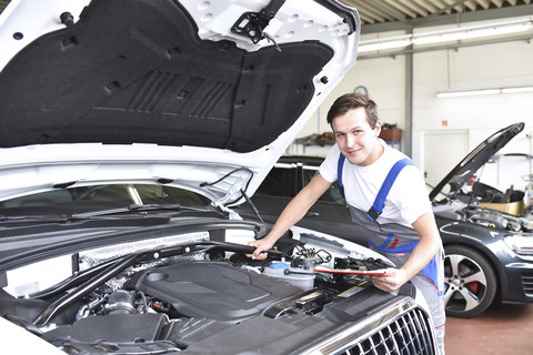 Mechaniker untersucht den Motor eines Autos in einer Werkstatt, lizenzfreies Stockfoto