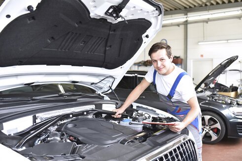 Mechaniker untersucht den Motor eines Autos in einer Werkstatt - LYF000444