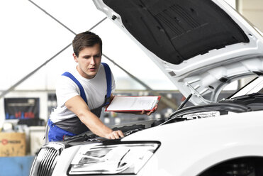 Mechanic examining engine of a car in a garage - LYF000432