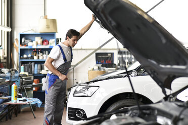 Mechaniker untersucht den Motor eines Autos in einer Werkstatt - LYF000433