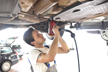 Mechaniker bei der Reparatur des Unterbodens eines Autos in einer Werkstatt - LYF000448