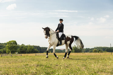 Woman riding horse on a meadow - TAM000218