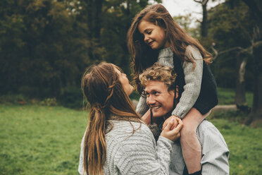 Glückliches junges Paar mit kleinem Mädchen auf den Schultern ihres Vaters im herbstlichen Park - CHAF000241