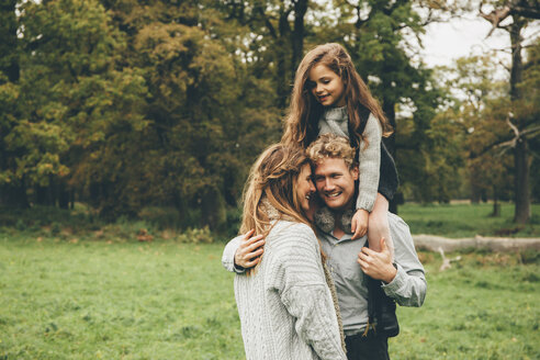 Junges Paar mit kleinem Mädchen auf den Schultern ihres Vaters im herbstlichen Park - CHAF000242