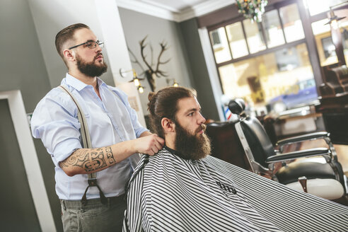 Barbier bindet sich einen Umhang um den Kunden - MADF000344