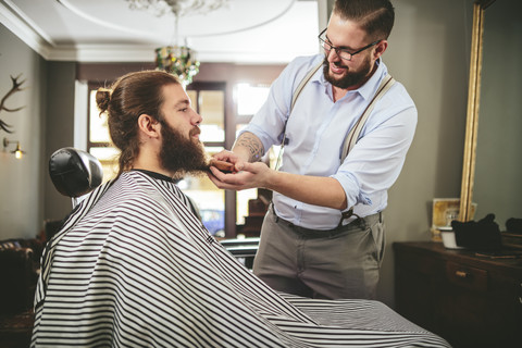 Friseur bürstet den Bart eines Kunden, lizenzfreies Stockfoto