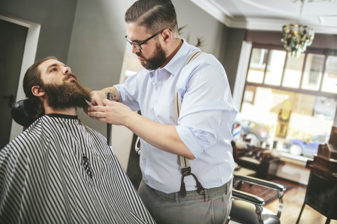 Barbier schneidet Bart eines Kunden, lizenzfreies Stockfoto