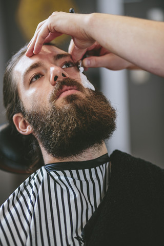 Mann mit Vollbart lässt sich beim Friseur rasieren, lizenzfreies Stockfoto