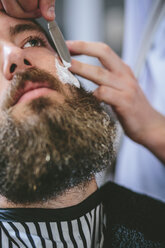 Mann mit Vollbart lässt sich beim Friseur rasieren - MADF000350