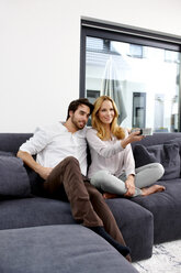 Couple sitting together on couch watching TV show - CHAF000281