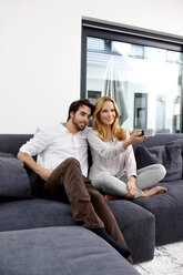 Paar sitzt zusammen auf der Couch und sieht eine Fernsehsendung - CHAF000281