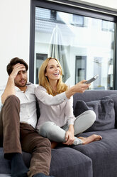Couple sitting together on couch watching TV show - CHAF000282