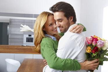 Young woman holding bunch of flowers hugging her boyfriend at home - CHAF000286