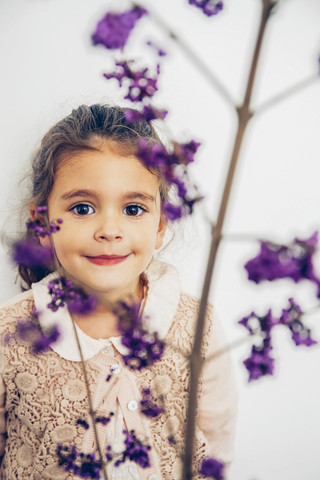 Porträt eines lächelnden Mädchens hinter einer Blüte, lizenzfreies Stockfoto