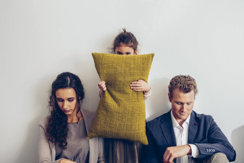 Couple having relationship conflict with their daughter hiding her face behind cushion - CHAF000323
