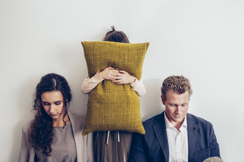 Couple having relationship conflict with their daughter hiding her face behind cushion - CHAF000324