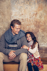 Lächelnder Vater und Tochter sitzen auf einer Holzbank - CHAF000337