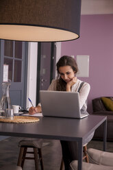 Young woman sitting at table using laptop - CHAF000344