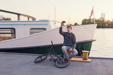 Deutschland, Hamburg, Teenager, der ein Selfie auf einem Bootssteg macht - MEMF000815