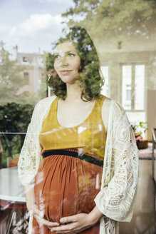 Porträt einer schwangeren Frau, die durch das Fenster schaut - MFF001791