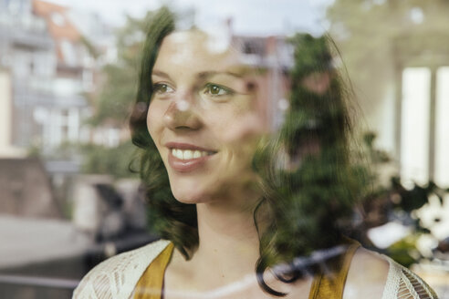 Porträt einer Frau, die durch das Fenster schaut - MFF001792